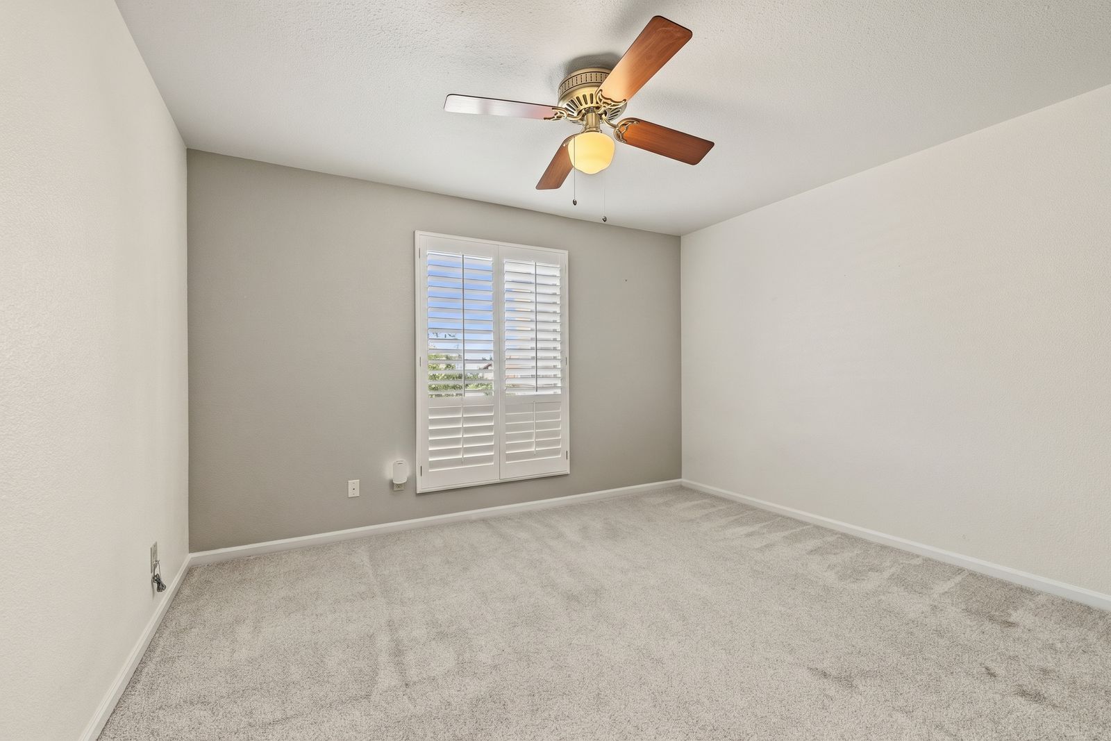 Bedroom with an accent wall and plantation shutters