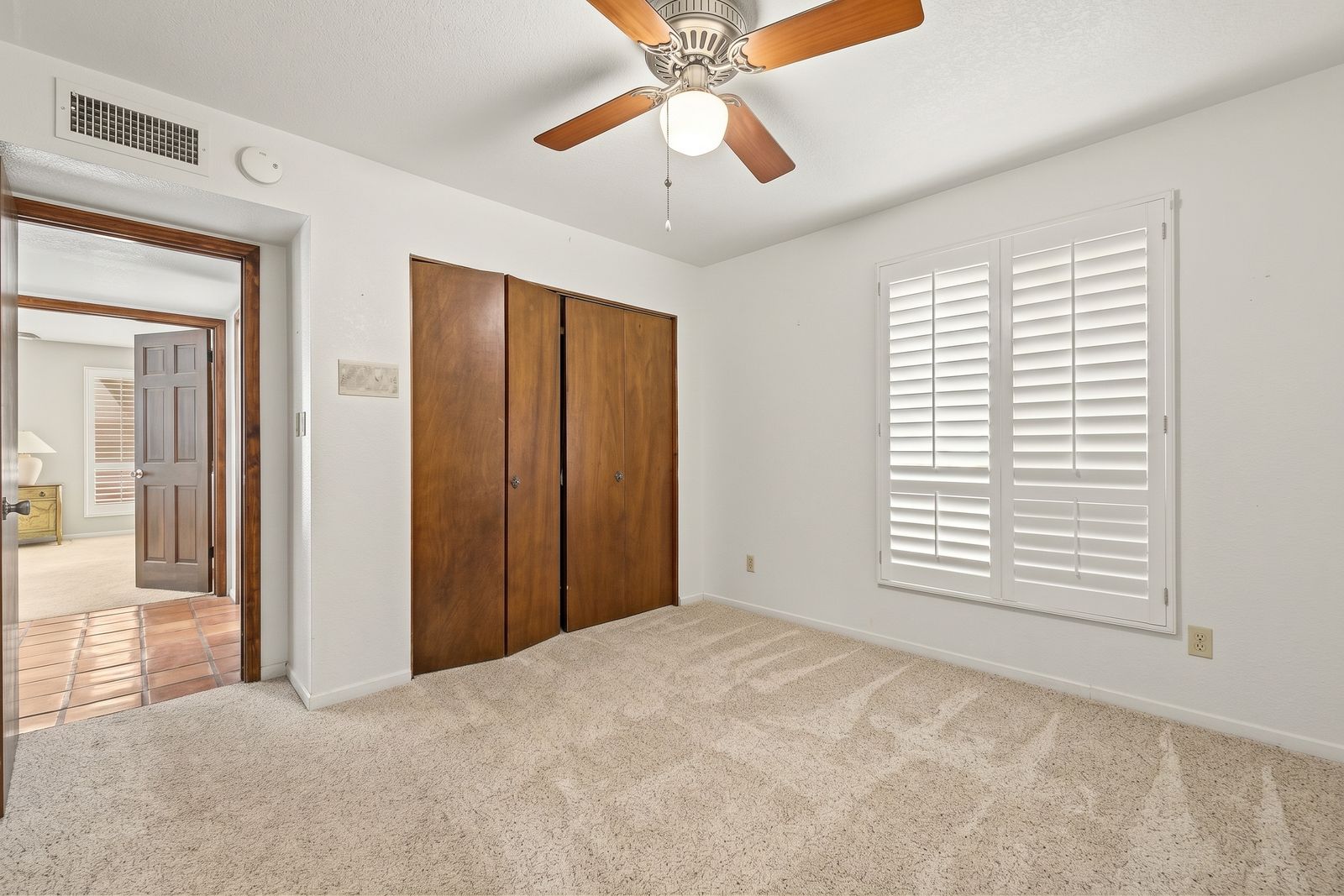 Bedroom with a wood-panel closet and plantation shutters