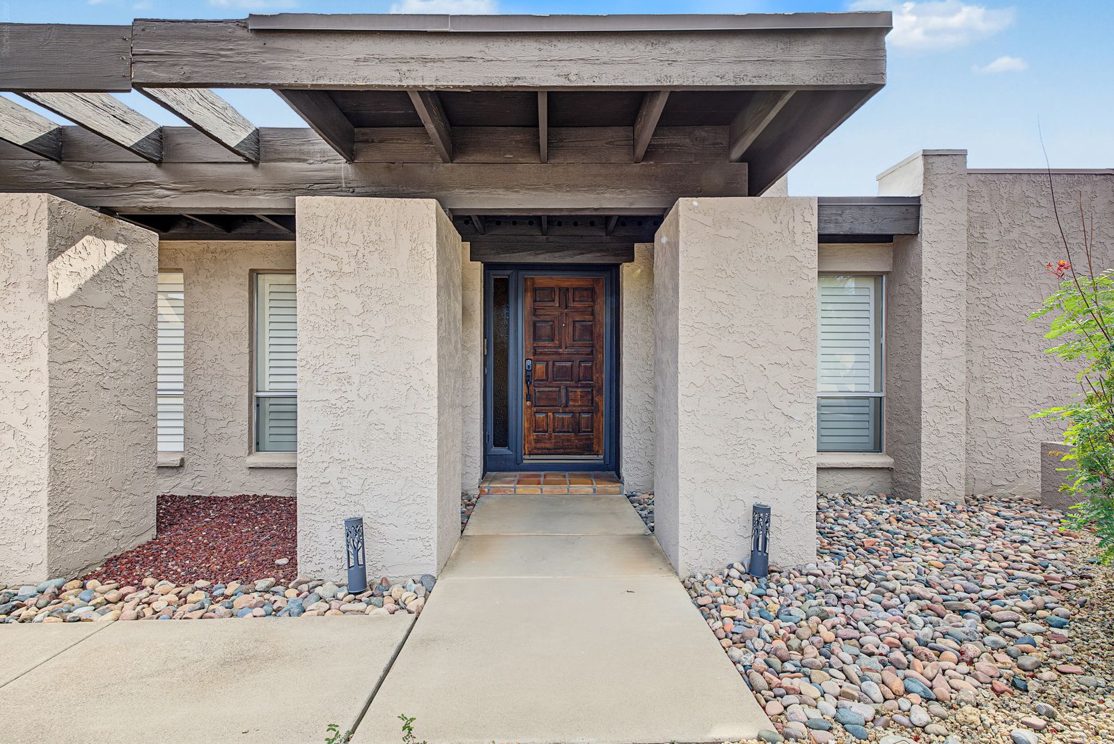 Covered front entry with a carved wood door