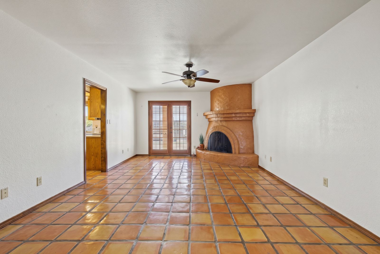 Family room with Saltillo tile, a beehive fireplace and French doors to the backyard