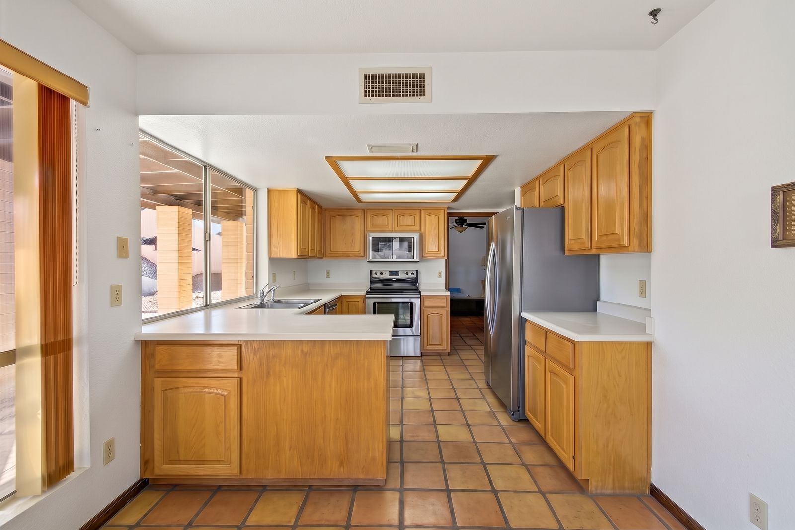 Kitchen with oak cabinets, stainless appliances and Saltillo tile