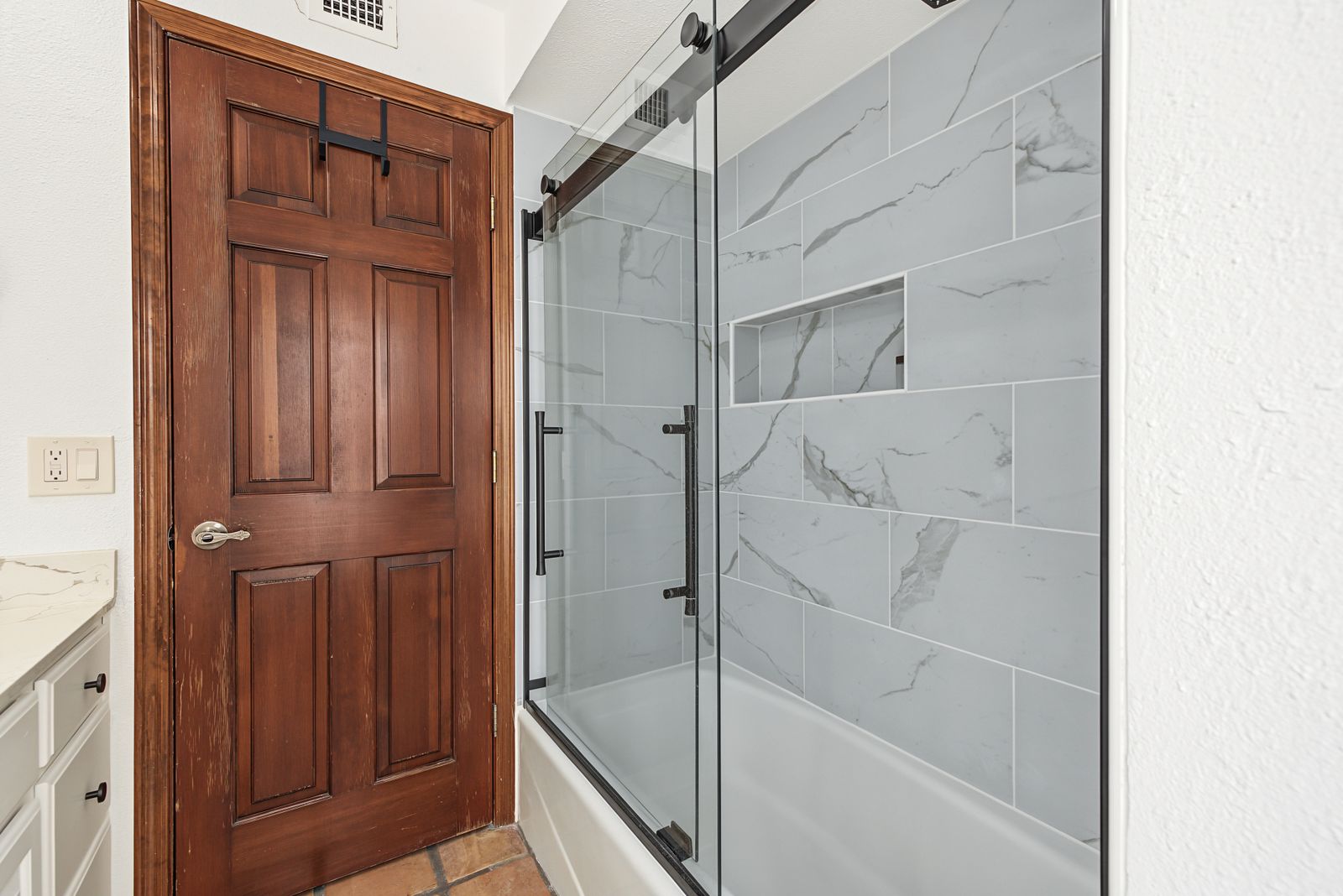 Updated tub and shower with a glass slider and marble-look tile